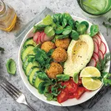 Un plato vibrante con falafel, aguacate, pepino, tomate y rábano, ideal para una dieta flexitariana equilibrada.