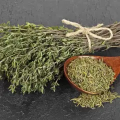 Manojo de tomillo fresco atado con cuerda y una cuchara de madera llena de tomillo seco, listo para preparar una infusión de tomillo.