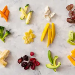 Variedad de alimentos cortados para blw bebe: zanahoria, calabacín, brócoli, pasta, mango, aguacate, plátano, bayas, kiwi y queso.