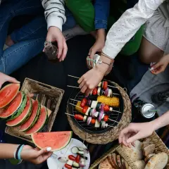 Disfrutando de una barbacoa vegetariana al aire libre con amigos, con brochetas de verduras a la parrilla, sandía y pan.