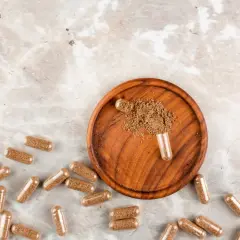 Cápsulas de maca, un superalimento en polvo, sobre un plato de madera. Descubre qué es la maca y sus beneficios.