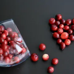 Arándanos rojos en forma de corazón y en una copa, ideales para infusiones y para saber para qué sirve la gayuba.