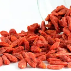 Un frasco de vidrio derrama bayas de goji, destacando sus vibrantes bayas rojas y sus innumerables propiedades beneficiosas.