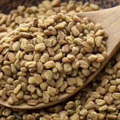 Cuchara de madera llena de semillas de fenogreco. El fenogreco para que sirve es un tema de interés, conocido por sus usos culinarios y medicinales.