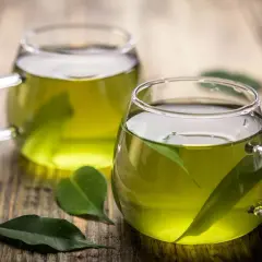 Dos tazas de té verde en vasos de cristal, con hojas flotando. Descubre para qué sirve el té verde y sus beneficios.