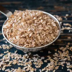 Cuchara llena de salvado de trigo, un ingrediente saludable y versátil para tus desayunos.