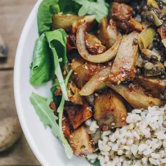 Un plato con seitan que es una proteína vegetal deliciosa, lentejas, arroz integral y hojas verdes.