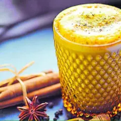 Vaso de leche dorada con canela, anís estrellado y jengibre.