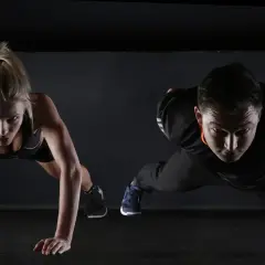Hombre y mujer en posición de plancha, sintiendo el ardor del ácido láctico en sus músculos.