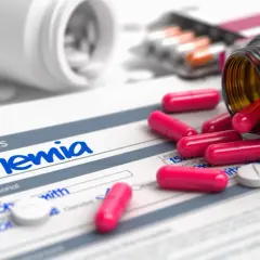 Pastillas rosas y blancas sobre un formulario de diagnóstico de anemia. Un frasco de suplemento de hierro derramado.