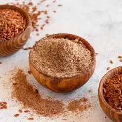 Tres cuencos de madera con semillas de lino enteras y molidas. Las semillas de lino son un superalimento versátil.