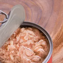 Atún en lata, un alimento práctico para el embarazo, con su tapa abierta sobre una superficie de madera.