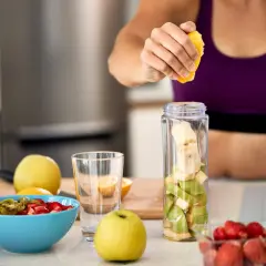 Mujer prepara batido de frutas. Ideal para saber **que tomar para las agujetas** y recuperarse tras el ejercicio.