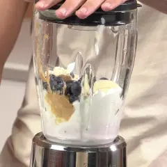 Ingredientes para batidos de proteínas: arándanos, plátano, crema y mantequilla de cacahuete en una licuadora.