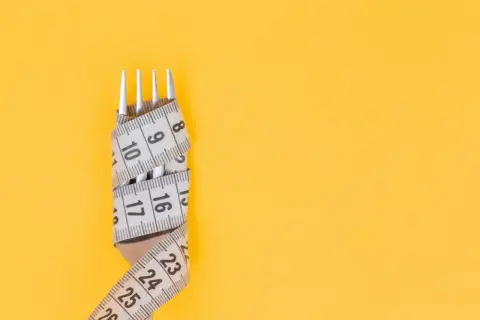Tenedor envuelto en cinta métrica, símbolo de la dieta Pronokal y control de peso.