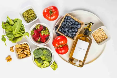 Ingredientes para una dieta antiinflamatoria menopausia: espinacas, fresas, arándanos, brócoli, tomates, nueces, semillas de calabaza, avena y aceite de oliva.