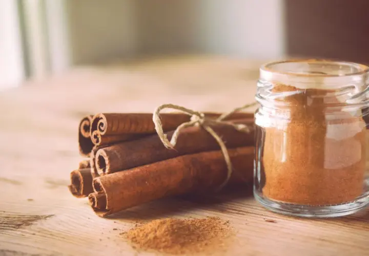 Canela en rama y en polvo en un frasco, destacando sus maravillosas canela propiedades para la salud y la cocina.