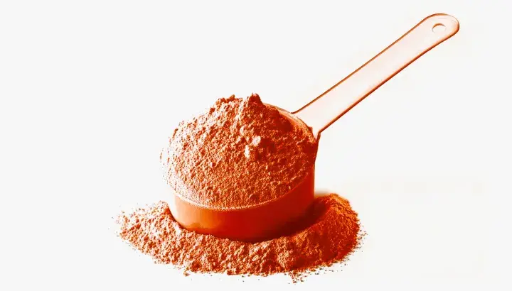 Una cuchara naranja llena de polvo de whey, ideal para tus batidos post-entreno.