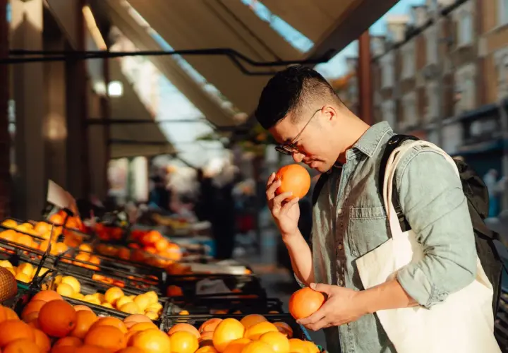 Hombre comprando naranjas, ricas en ácido ascórbico para que sirve: vitamina C para la salud.