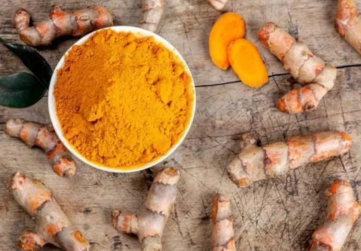 Raíces de cúrcuma y polvo dorado. Descubre para qué sirve la cúrcuma y sus beneficios.