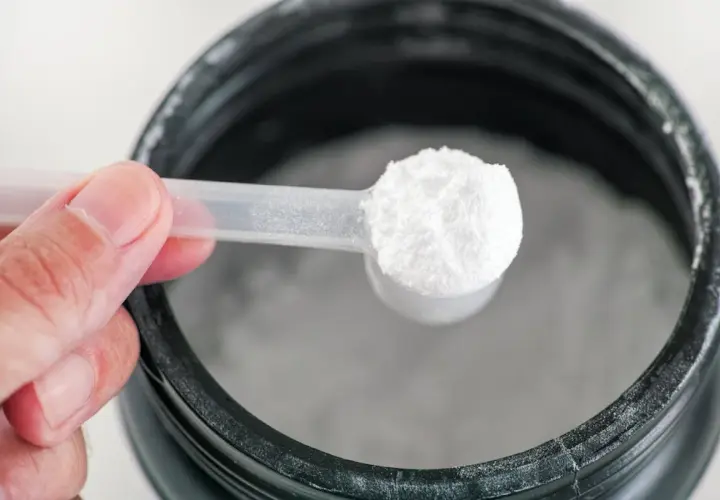 Una cuchara con polvo blanco, posiblemente glutamina para que sirve en la recuperación muscular.