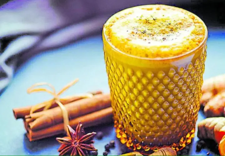 Vaso de leche dorada con canela, anís estrellado y jengibre.