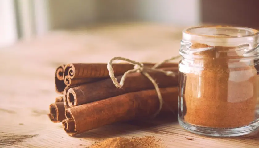 Canela en rama y en polvo en un frasco, destacando sus maravillosas canela propiedades para la salud y la cocina.