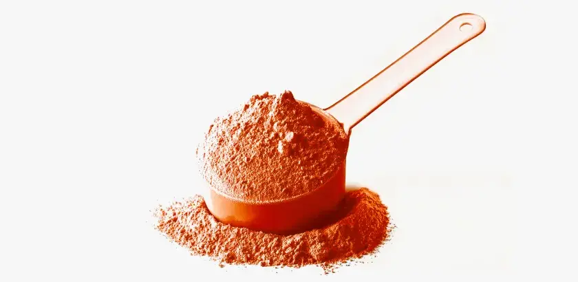 Una cuchara naranja llena de polvo de whey, ideal para tus batidos post-entreno.