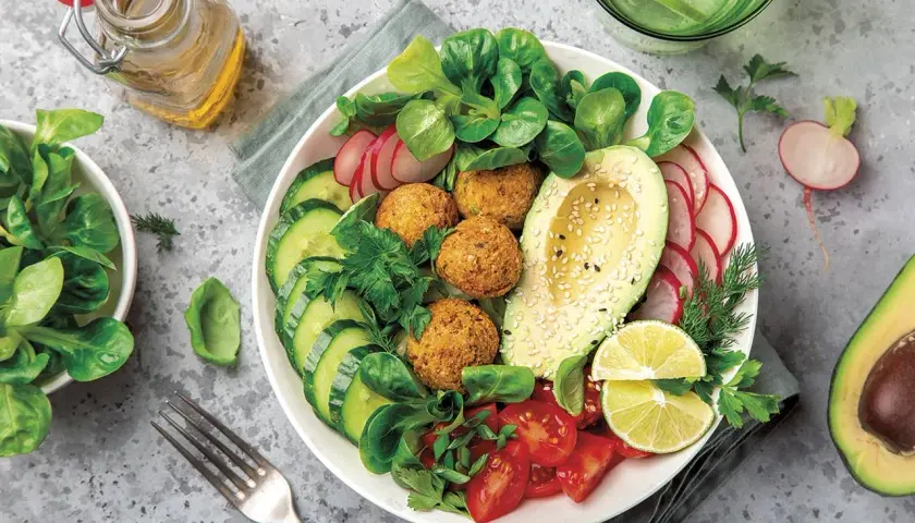 Un plato vibrante con falafel, aguacate, pepino, tomate y rábano, ideal para una dieta flexitariana equilibrada.