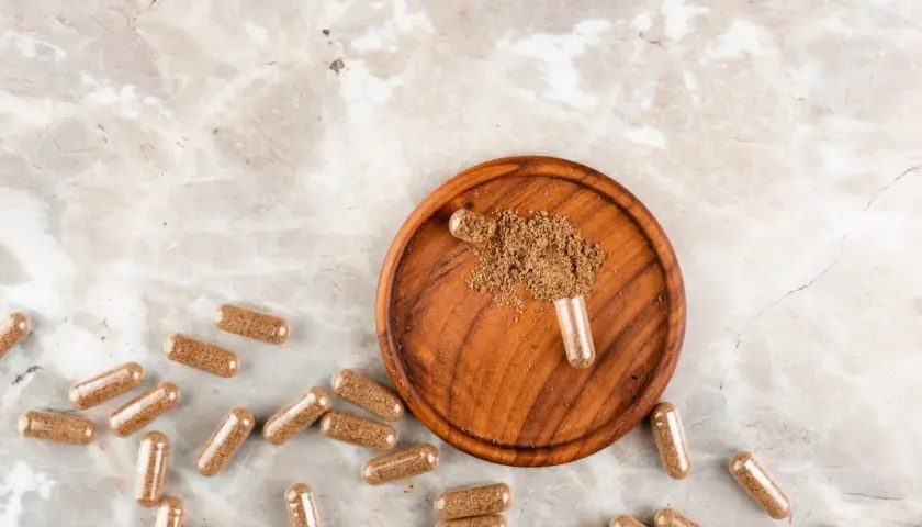 Cápsulas de maca, un superalimento en polvo, sobre un plato de madera. Descubre qué es la maca y sus beneficios.