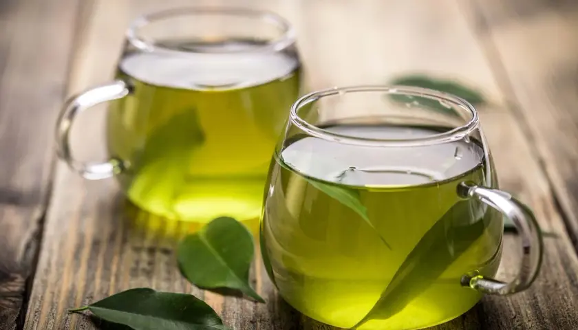 Dos tazas de té verde en vasos de cristal, con hojas flotando. Descubre para qué sirve el té verde y sus beneficios.