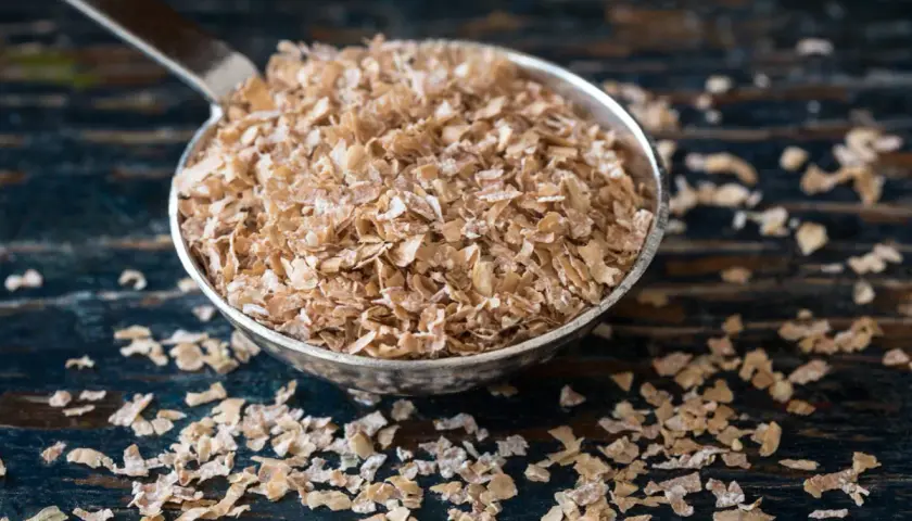 Cuchara llena de salvado de trigo, un ingrediente saludable y versátil para tus desayunos.