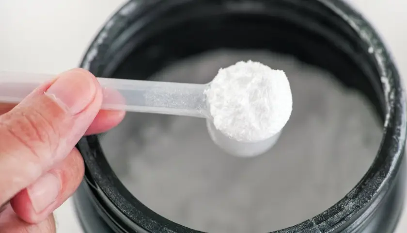Una cuchara con polvo blanco, posiblemente glutamina para que sirve en la recuperación muscular.