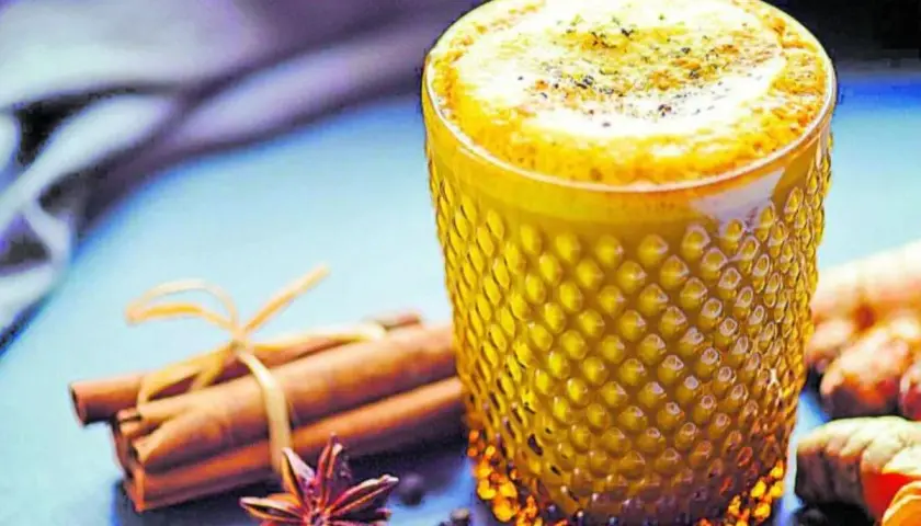 Vaso de leche dorada con canela, anís estrellado y jengibre.
