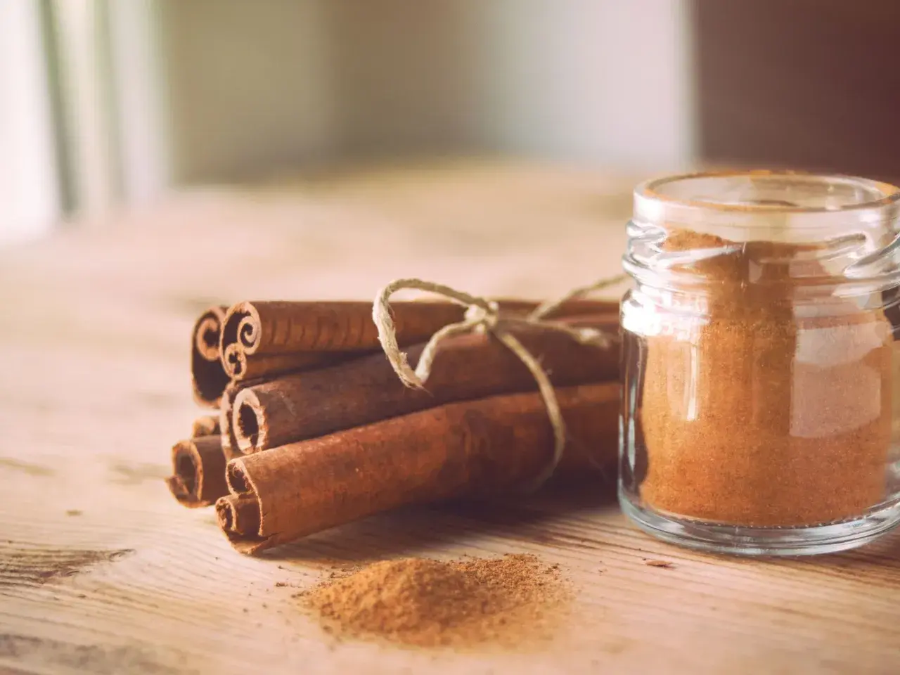 Canela en rama y en polvo en un frasco, destacando sus maravillosas canela propiedades para la salud y la cocina.