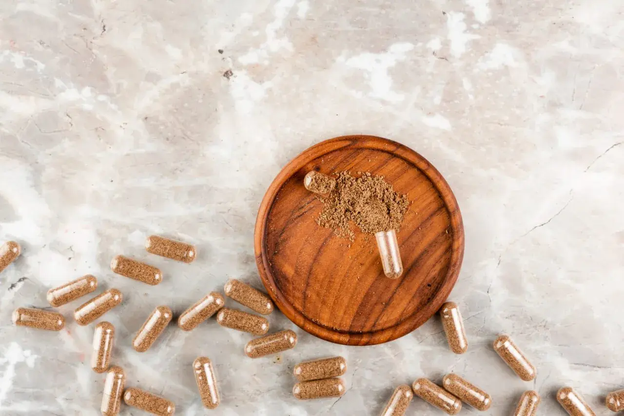 Cápsulas de maca, un superalimento en polvo, sobre un plato de madera. Descubre qué es la maca y sus beneficios.