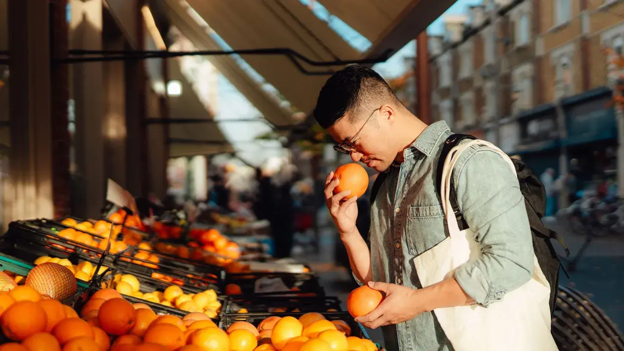Hombre comprando naranjas, ricas en ácido ascórbico para que sirve: vitamina C para la salud.
