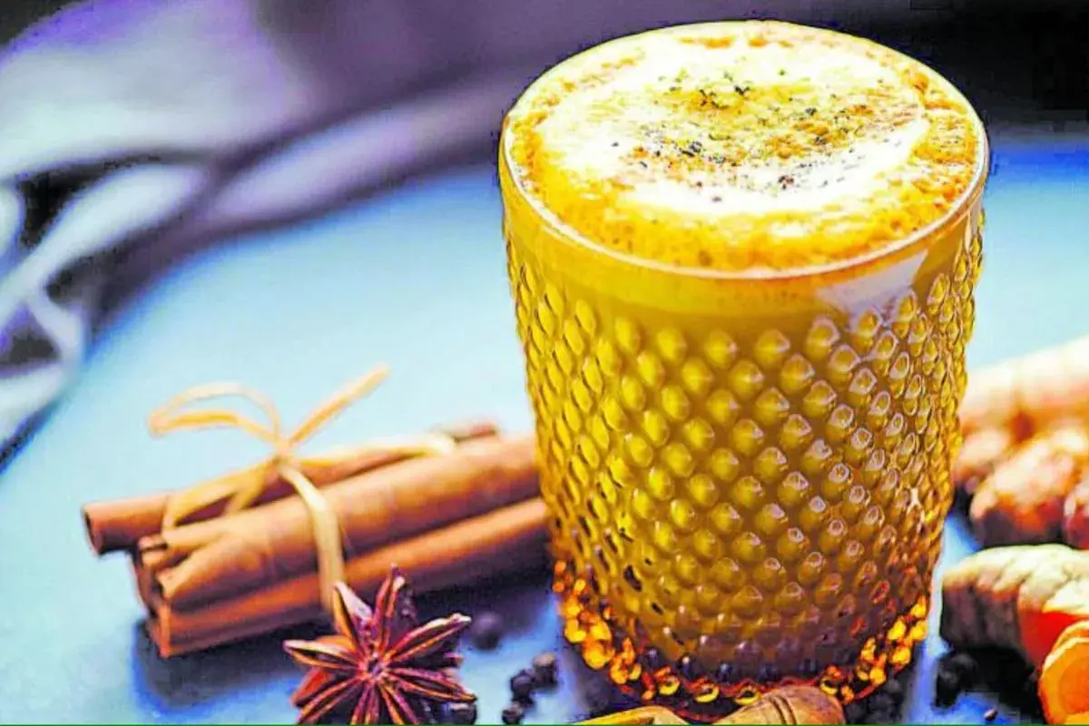 Vaso de leche dorada con canela, anís estrellado y jengibre.