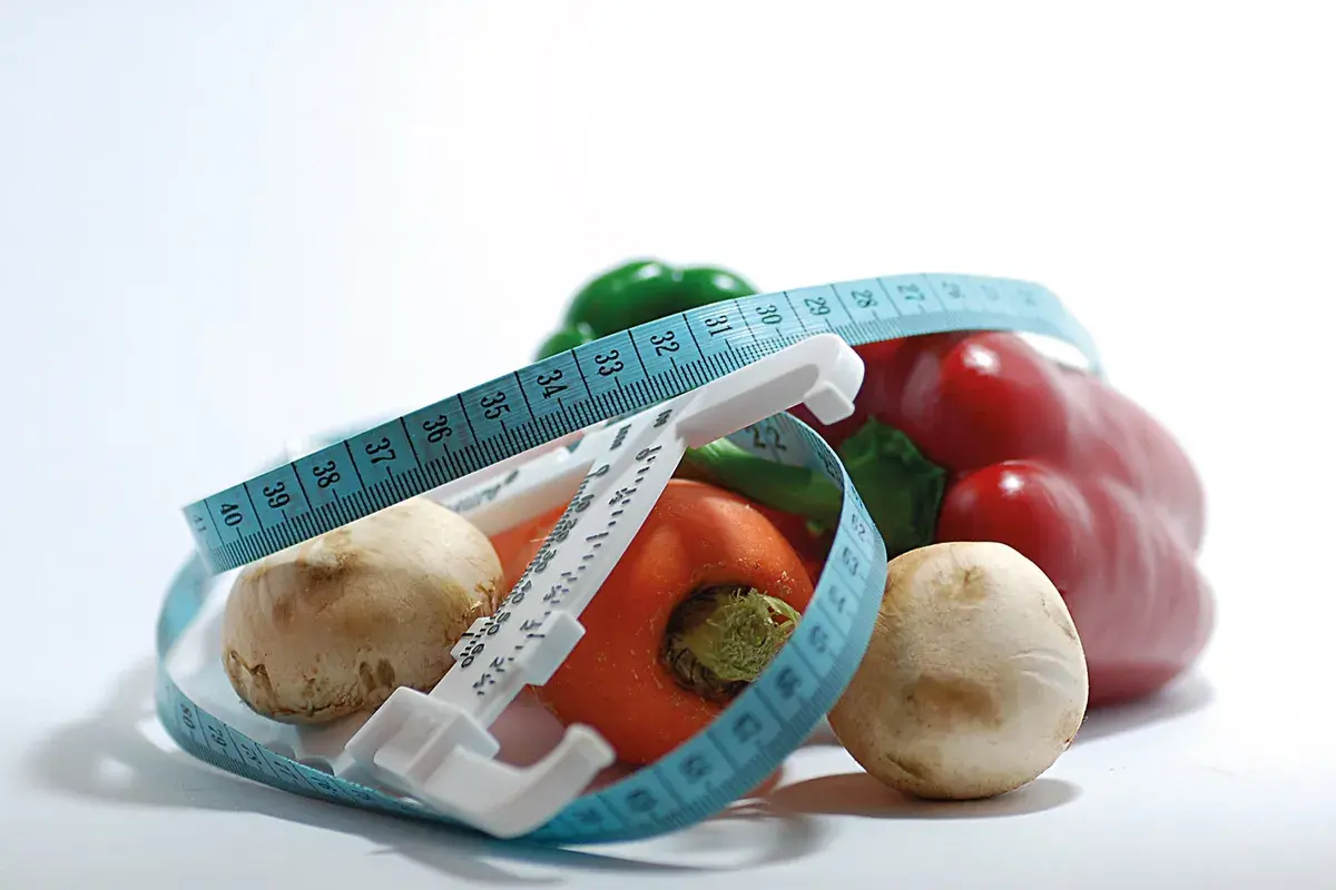 Verduras frescas y cinta métrica, símbolos de dietas milagro y un estilo de vida saludable.