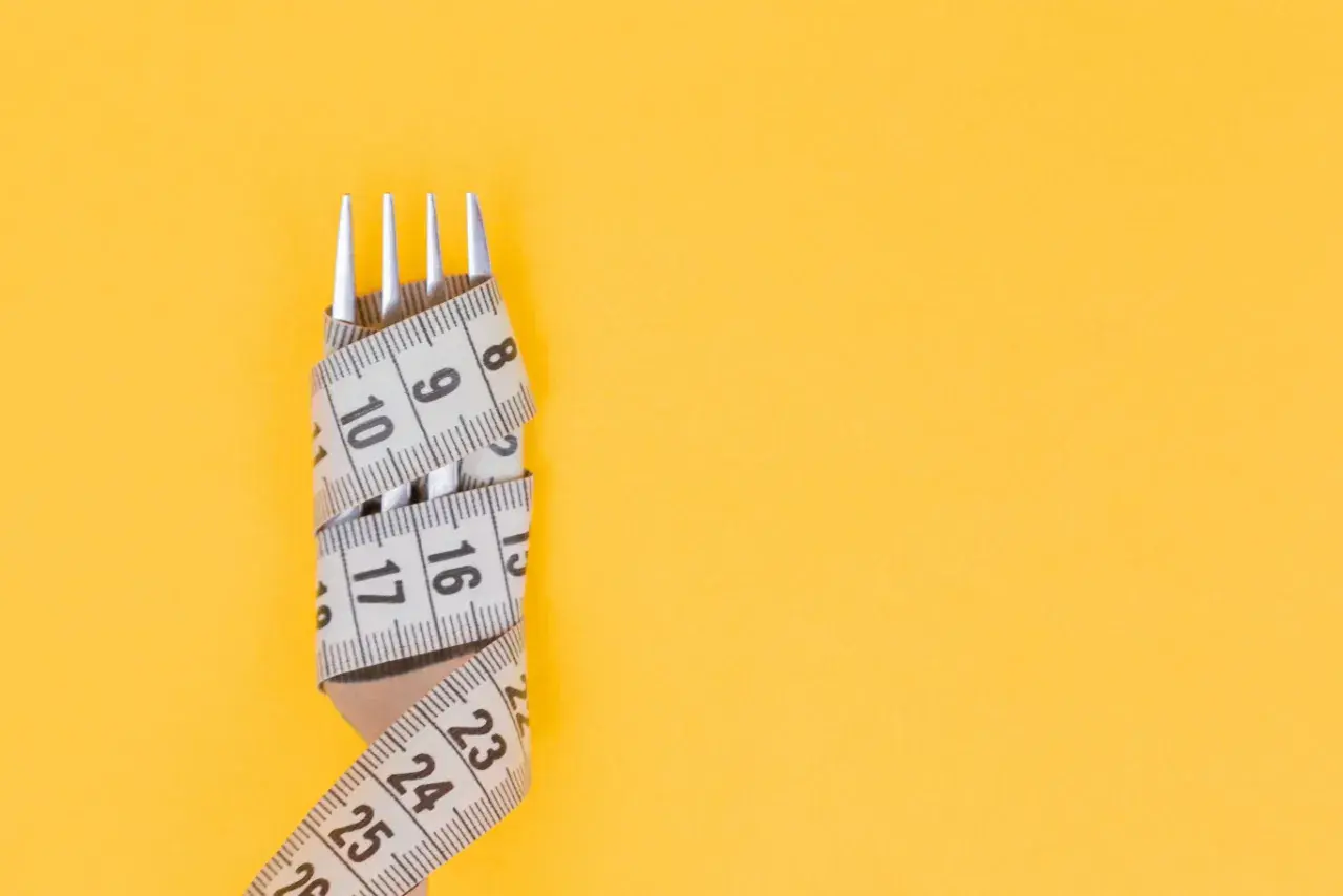 Tenedor envuelto en cinta métrica, símbolo de la dieta Pronokal y control de peso.