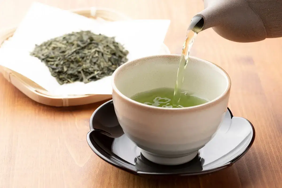 T&eacute; verde reci&eacute;n servido en una taza, con hojas secas al lado. Descubre para qu&eacute; sirve el t&eacute; verde y sus beneficios.