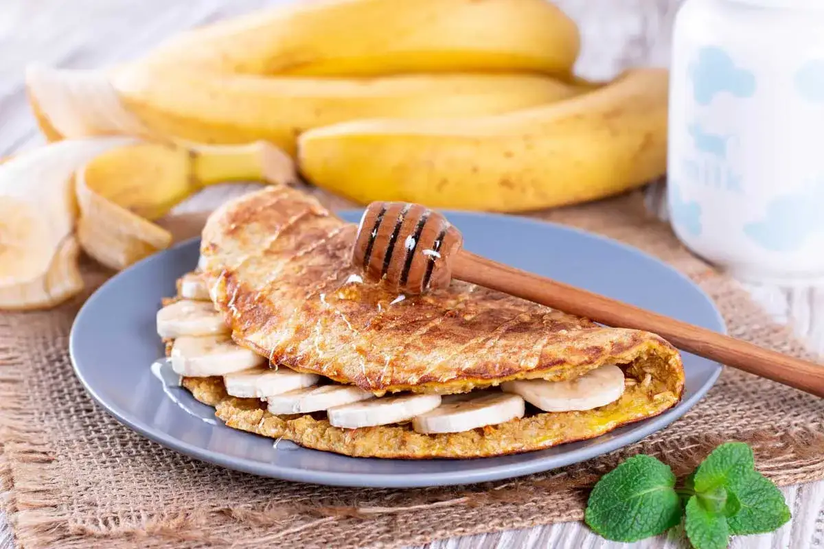 Tortitas fit de avena y pl&aacute;tano, cubiertas con miel y rodajas de pl&aacute;tano fresco. Un desayuno saludable y delicioso.