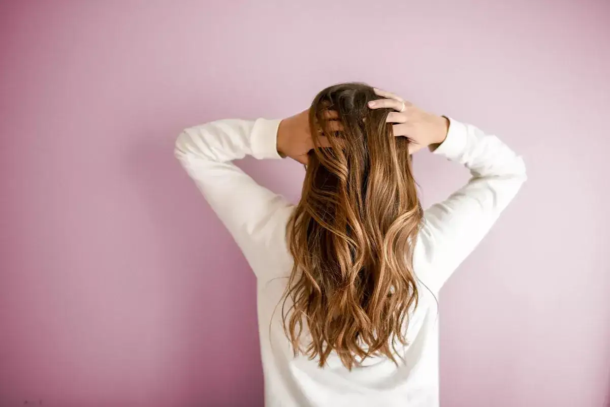 Cabello largo y ondulado, con las manos en la nuca. &iquest;Te preguntas la vitamina H para qu&eacute; sirve? Para un cabello sano y fuerte.