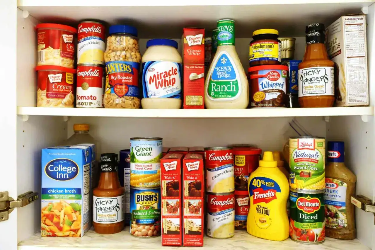 Estante lleno de alimentos no perecederos: sopas, aderezos, conservas, condimentos y m&aacute;s.