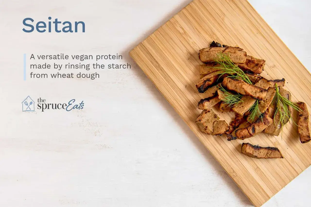 Seitan, proteína vegana versátil hecha de masa de trigo. Trozos dorados y a la parrilla con eneldo fresco sobre tabla de madera.