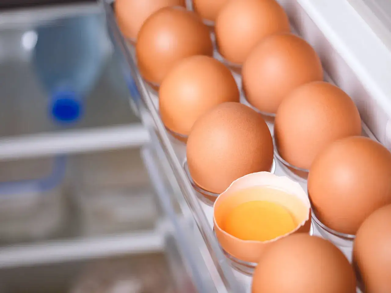 Huevos marrones en la nevera, uno roto mostrando la yema. &iquest;Cu&aacute;nto dura un huevo desde que lo pone la gallina?