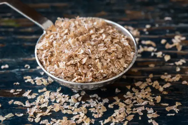 Cuchara llena de salvado de trigo, un ingrediente saludable y versátil para tus desayunos.